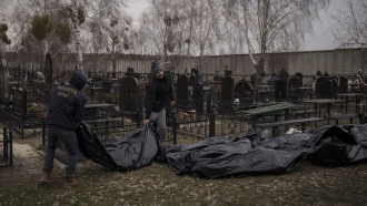 Workers carry bodies of people found dead to a cemetery in Bucha.