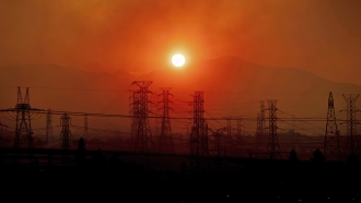 The sun rises above power lines in California.