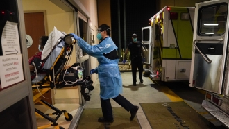 Emergency techs push a gurney into a hospital.