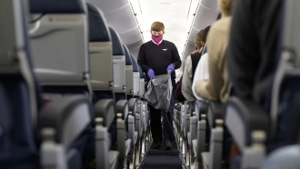 A Delta Airlines flight attendant walks down the aisle of a plane.