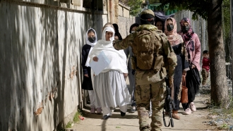 A Taliban fighter stops the women who want to enter the government passport office in Kabul.