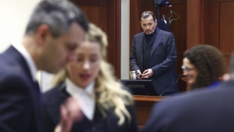 Actor Amber Heard speaks with her legal team as actor Johnny Depp stands at the Fairfax County Circuit Court.