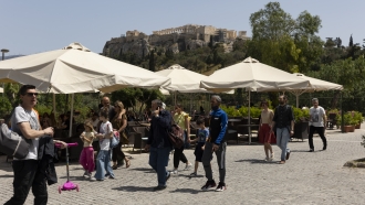 People make their way on a pedestrian street at the foot of the Acropolis hill, in Athens
