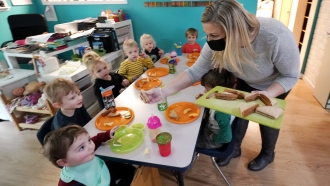A woman serves lunch to preschoolers at her Forever Young Daycare facility