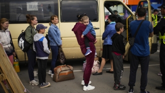 People wait to be processed upon their arrival at a reception center for displaced people in Zaporizhzhia, Ukraine