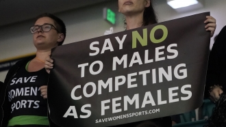 Protester holds sign as transgender athlete Lia Thomas competes at the NCAA Swimming and Diving Championships