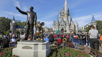 Guests watch a show near a statue in Walt Disney World.