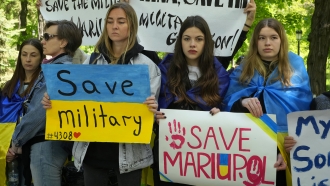 Ukrainian women hold signs about saving Ukraine