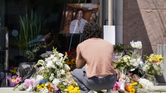 A neighbor of Dr. John Cheng kneels at a memorial for him