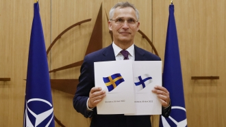 NATO Secretary-General Jens Stoltenberg displays documents as Sweden and Finland applied for membership.