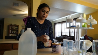 A woman prepares a bottle of baby formula for her infant son.