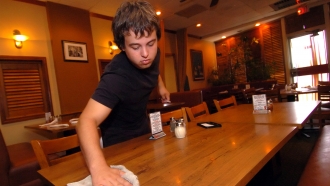 A teen clears a table in Vito's Pizzaria and Restaurant.