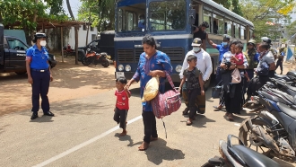 Police bring a group of people, who were attempting to travel illegally to Australia, to a police station in Sri Lanka