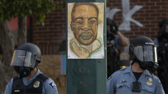 Minneapolis police stand in front of an image of George Floyd