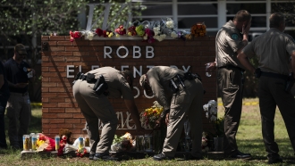 Two Texas Troopers light a candle at a memorial at Robb Elementary School in Uvalde, Texas