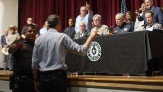 Beto O'Rourke approaches Texas Gov. Greg Abbott during a briefing.