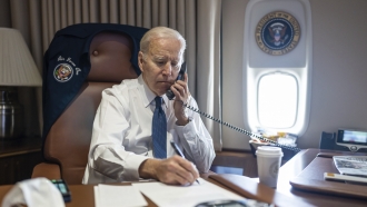 President Joe Biden talking with Texas Gov. Greg Abbott on the phone aboard Air Force One.