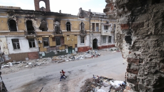 Children walk among buildings destroyed during fighting.