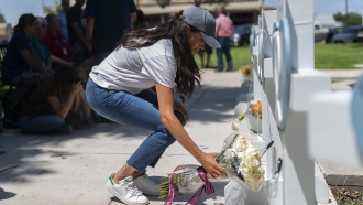 Meghan Markle, Duchess of Sussex, leaves flowers at a memorial site.