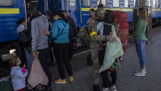 Two couples kiss during their reunion after three months of war-related separation at the Kharkiv train station