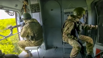 Russian soldiers control the situation sitting on a board of a Mi-8 helicopter of the Russian air force