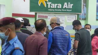 A signage of Tara Airlines is seen behind as a team of climbers prepare to leave for rescue operations from the airplane