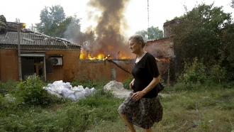 Woman flees a burning house in Ukraine