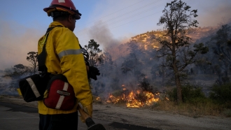 A firefighter watches as the Sheep Fire burns in Wrightwood, California