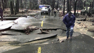 A man steps out of a washed-out section of roadway