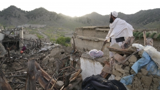 Afghan man stands among earthquake destruction