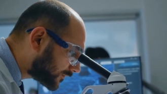 A man looks into a lab microscope