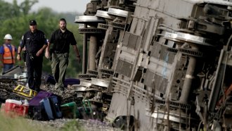 Law enforcement personnel inspect the scene of an Amtrak train which derailed after striking a dump truck.