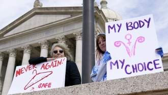 Dani Thayer, left, and Marina Lanae, right, both of Tulsa, Okla., hold pro-choice signs at the state Capitol