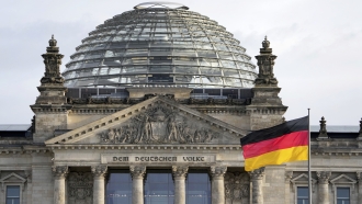 A national flag of Germany waves in front of the Reichag building, home of the German federal parliament Bundestag.