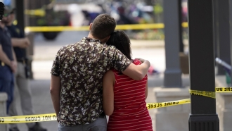 A couple looks toward the scene of the mass shooting in Highland Park, IL.