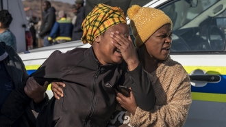 A woman weeps at the scene of an overnight bar shooting in Soweto, South Africa