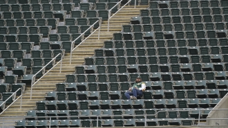 A man sits in the bleachers in a sports stadium.