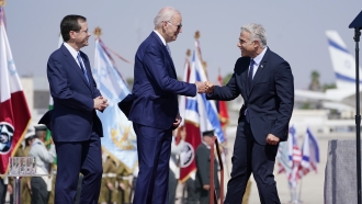 President Joe Biden is greeted by Israeli Prime Minister Yair Lapid, right and President Isaac Herzog, left.