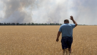 A farmer reacts as he looks at his burning field caused by the fighting at the front line in the Dnipropetrovsk region