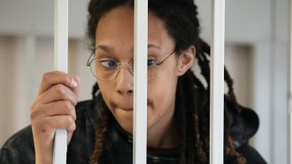 WNBA star and two-time Olympic gold medalist Brittney Griner stands in a cage at a court room.