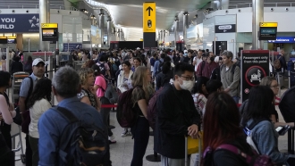 Travellers queue at security at Heathrow Airport in London