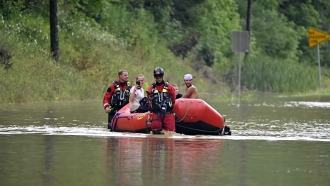 Members of the Winchester, Ky., Fire Department walk inflatable boats across flood waters