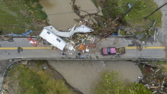 People work to clear a house from a bridge near the Whitesburg Recycling Center in Letcher County, Ky.
