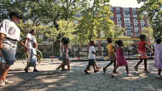 Children from a nearby daycare are escorted in Marcus Garvey Park in the Harlem neighborhood of New York.