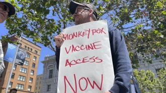 A man holds a sign urging increased access to the monkeypox vaccine during a protest in San Francisco.