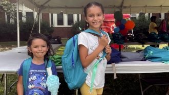 Two sisters pick out new backpacks at a Chicago Public Schools back-to-school supply giveaway.