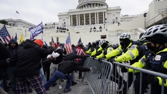 Insurrectionists loyal to President Donald Trump try to break through a police barrier.