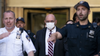 Law enforcement personnel escort the Trump Organization's former Chief Financial Officer Allen Weisselberg