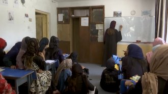 Teachers and students sit in a classroom in Afghanistan.
