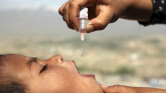 An Afghan health worker uses an oral polio vaccine on a child.